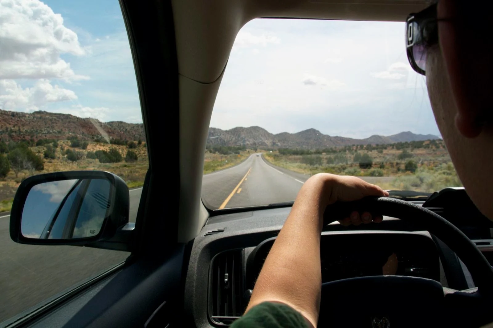 Driver following an open road through dry mountain hills